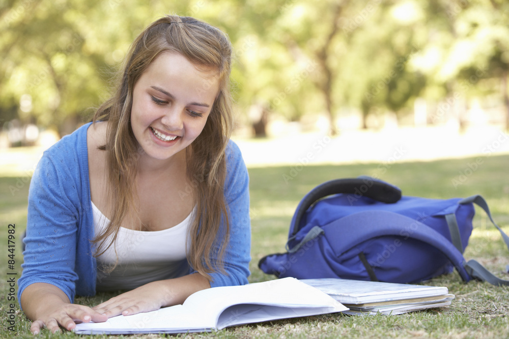 Female College Student Lying In Park Reading Textbook Female College Student Lying In Park Reading Textbook