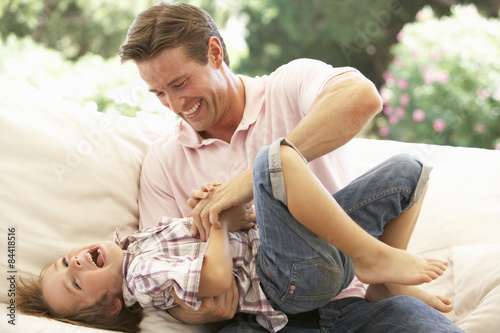 Fotografie Father With Son Laughing Together On Sofa