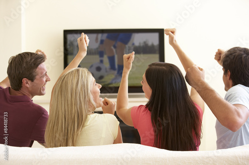 Group Of Friends Watching Widescreen TV At Home