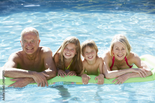 Grandparents And Grandchildren Relaxing In Swimming Pool Together
