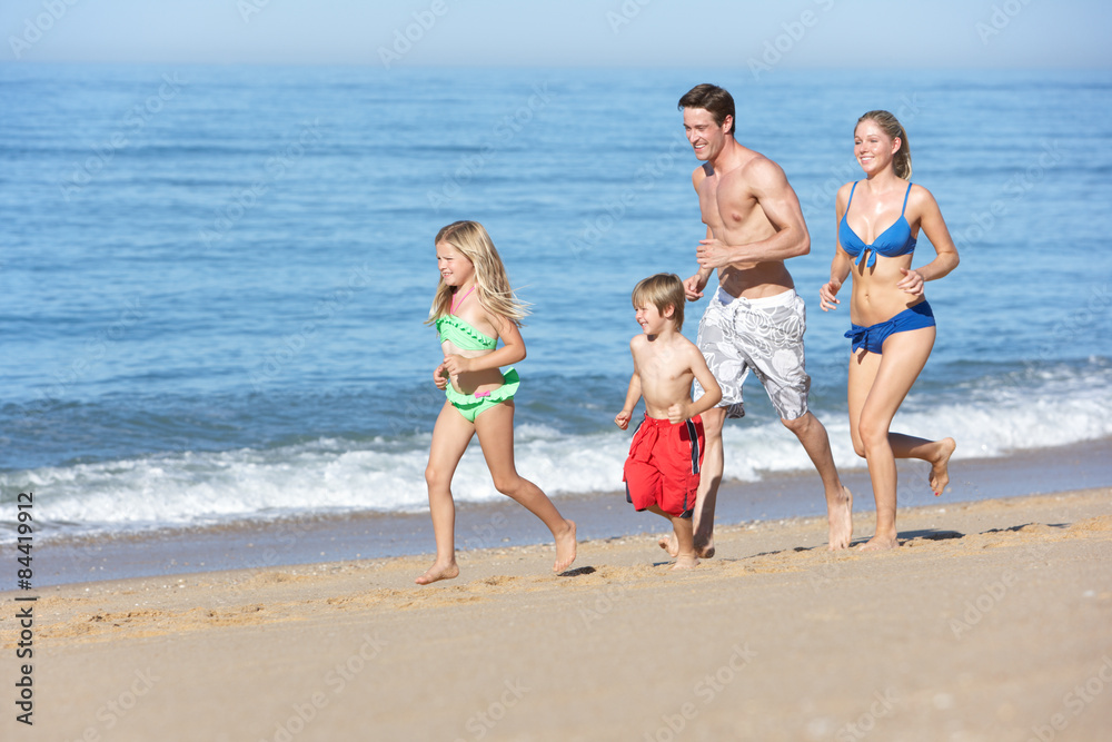Family Enjoying Beach Holiday Running Along Beach