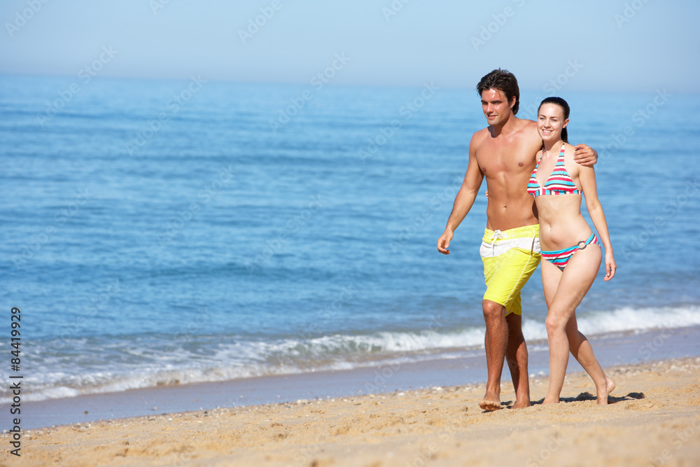 Young Couple Walking Along Summer Beach