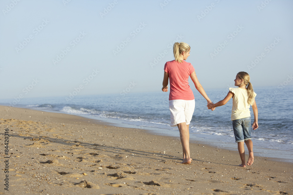 Mother And Daughter Enjoying Walk Along Beach