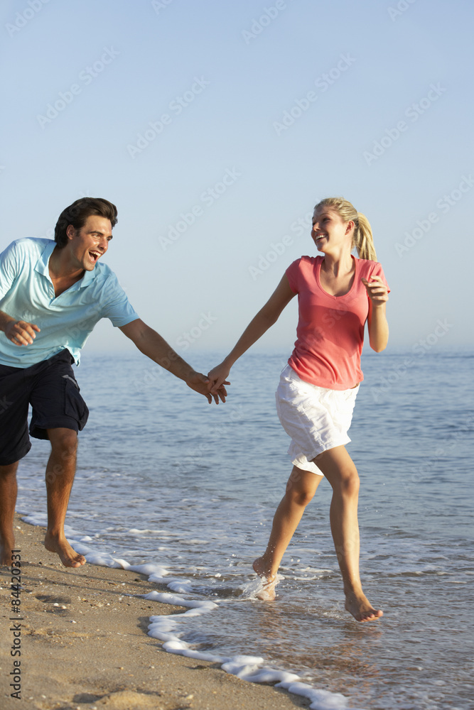 Young Couple Running Along Beach Young Couple Running Along Beach