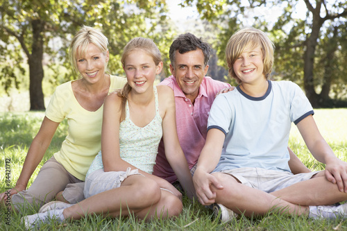 Middle Aged Family Sitting In Field In Countryside