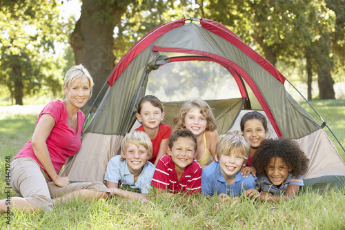 Group Of Children With Mother Having Fun In Tent In Countryside