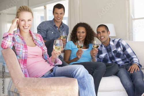 Group Of Friends Relaxing On Sofa Drinking Wine At Home Together