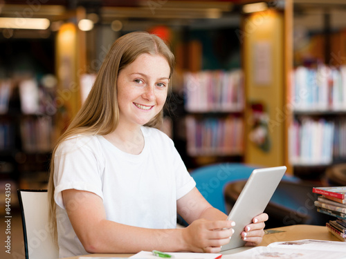 Teenage girl with tablet in library