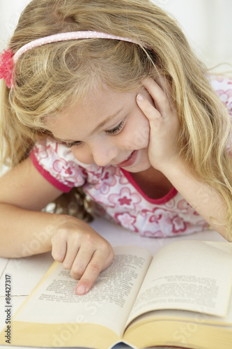 Young Girl Reading Book In Bedroom