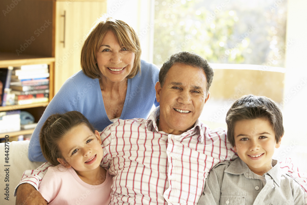 Hispanic Grandparents With Grandchildren Relaxing On Sofa At Hom Hispanic Grandparents With Grandchildren Relaxing On Sofa At Hom