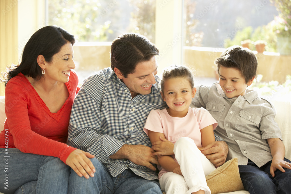 Young Hispanic Family Relaxing On Sofa At Home Young Hispanic Family Relaxing On Sofa At Home