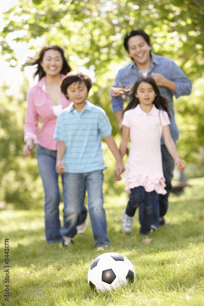 Asian family playing soccer in park Asian family playing soccer in park