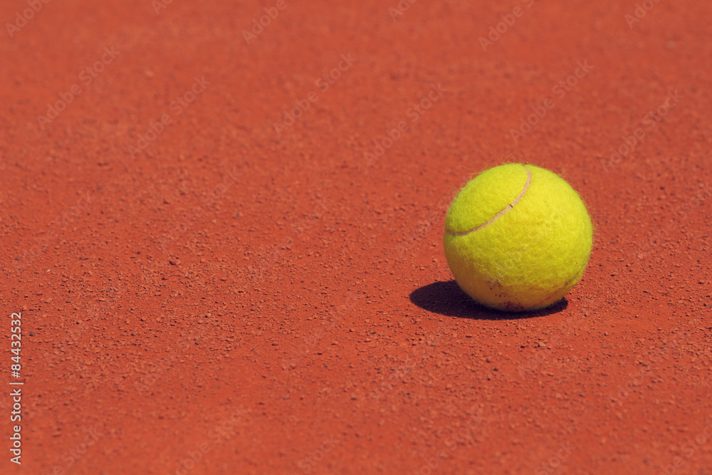 Tennis ball on a clay court.