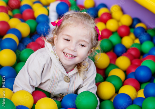 happy little girl playing on colorful balls