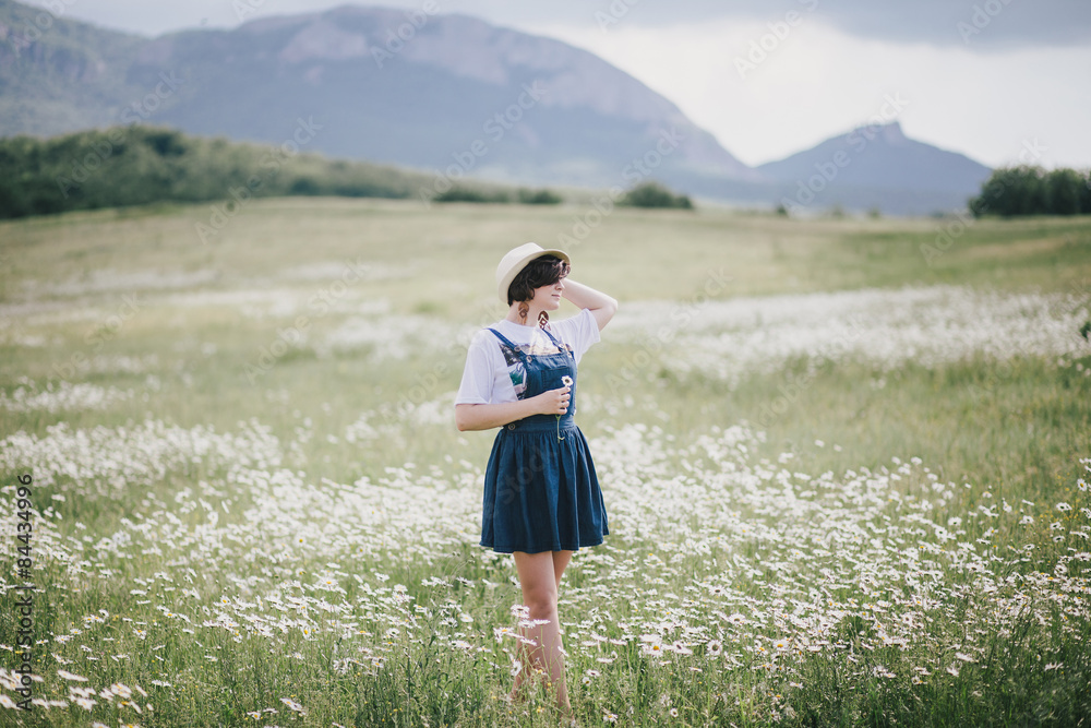 Beautiful young woman in a straw hat posing in a camomile field Beautiful young woman in a straw hat posing in a camomile field