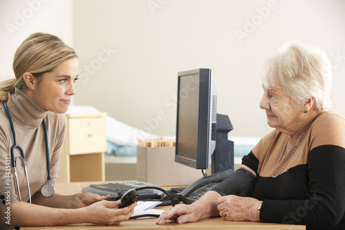 Doctor taking senior woman's blood pressure