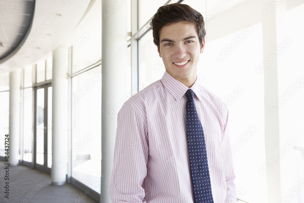 Portrait Of Young Businessman Standing In Corridor Of Modern Office Building Portrait Of Young Businessman Standing In Corridor Of Modern Office Building