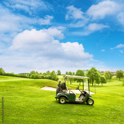 Golf course lanscape with a cart over blue sky