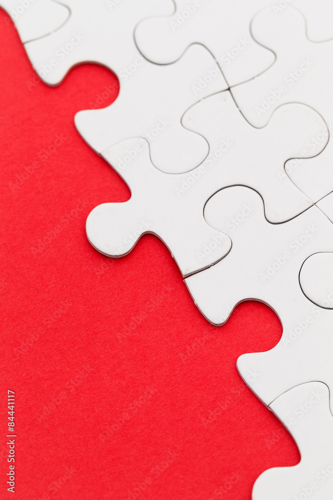 Fototapeta premium Blank white jigsaw puzzles on a bright red paper background