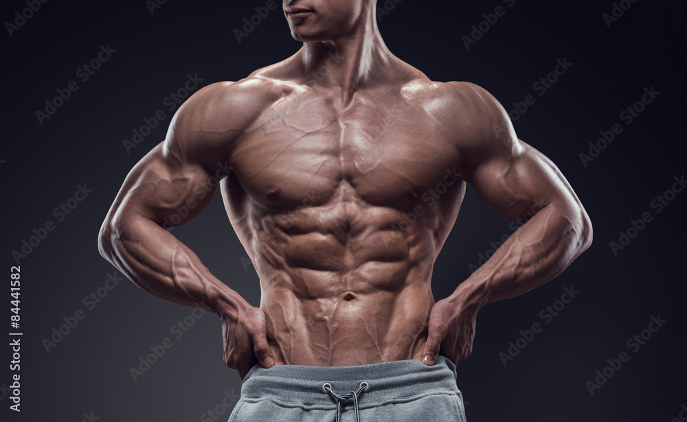 Muscular and fit young bodybuilder fitness male model posing over black background Muscular and fit young bodybuilder fitness male model posing over black background