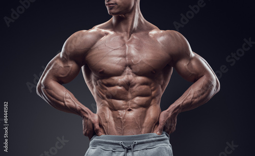 Платно Muscular and fit young bodybuilder fitness male model posing over black backgrou