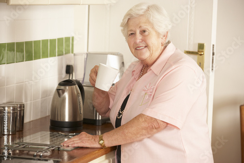 Retired Senior Woman In Kitchen Making Hot Drink