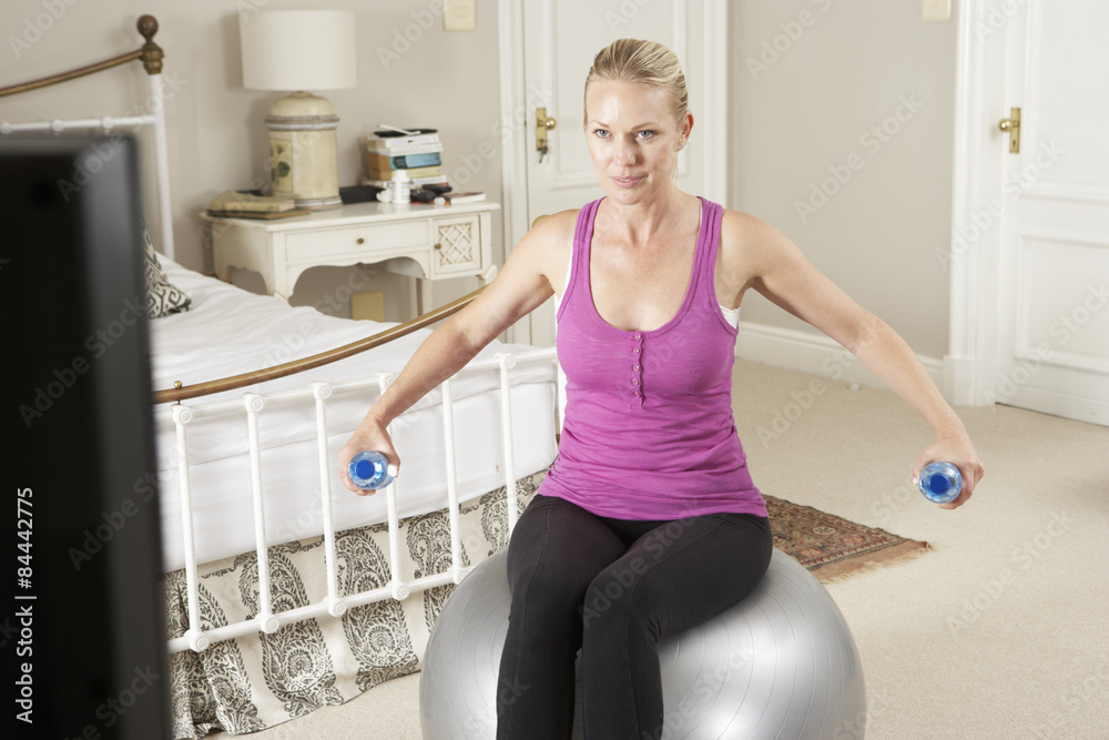 Woman Exercising Whilst Watching Fitness DVD On Television