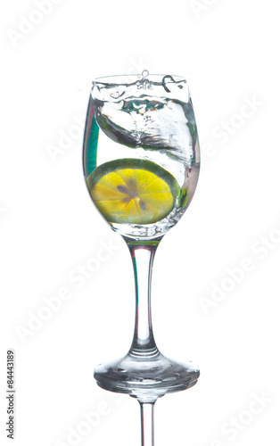 Lime splashing into glass of water on white background