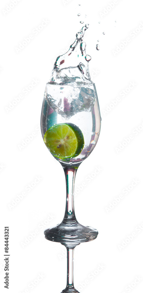 Lime splashing into glass of water on white background Lime splashing into glass of water on white background