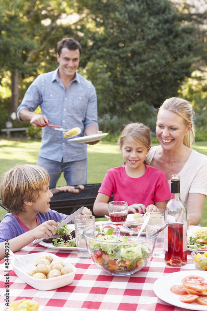 Family Enjoying Barbeque In Garden Together