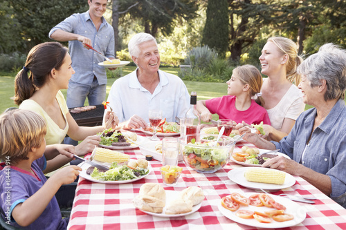 Three Generation Family Enjoying Barbeque In Garden Together
