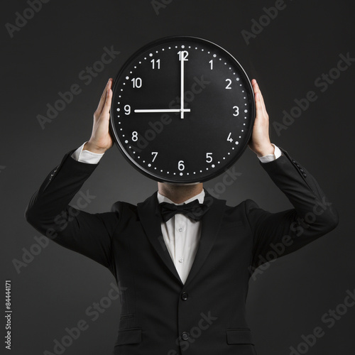 Handsome young man holding a clock