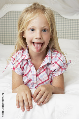 Young Girl Lying On Bed Pulling Funny Face