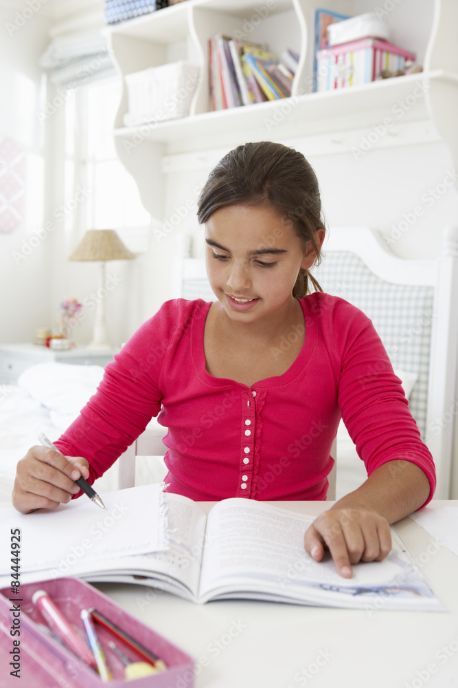 Young Girl Doing Homework At Desk In Bedroom Young Girl Doing Homework At Desk In Bedroom