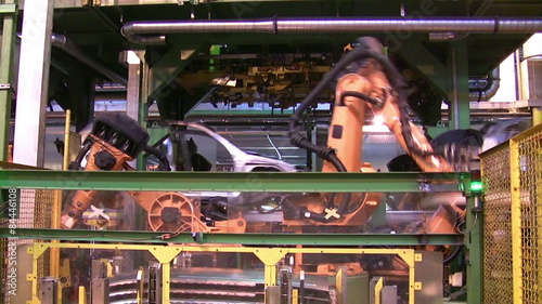 Robots weld car parts in production line at factory
