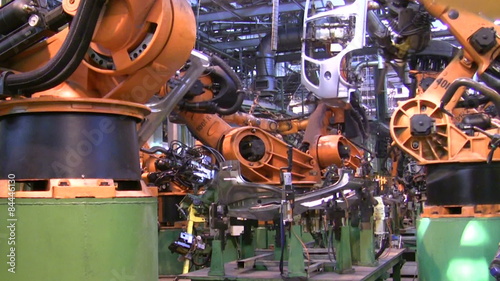 Robots weld car parts in production line at factory
