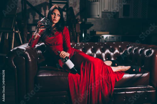 young woman in red dress sitting on leather sofa photo