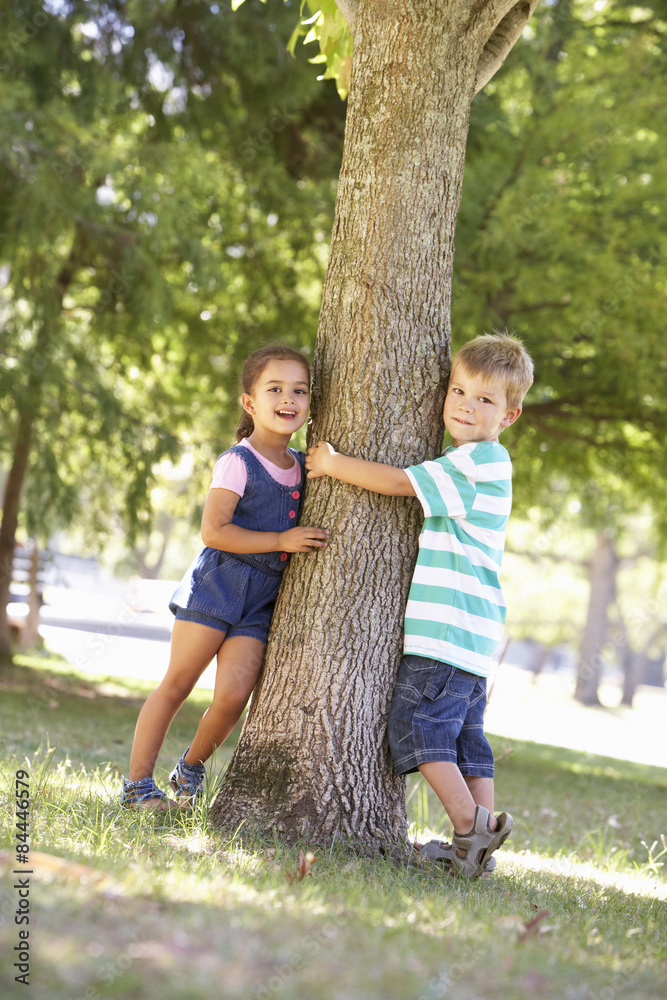 Fototapeta premium Two Children Hugging Tree In Park