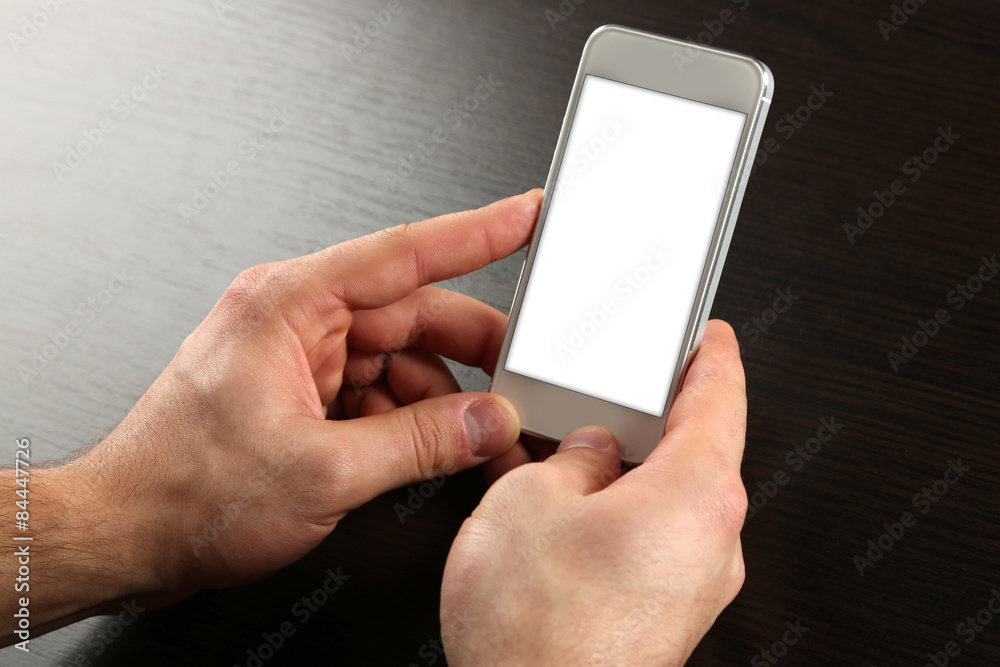 Hands holding smart mobile phone on wooden table background Hands holding smart mobile phone on wooden table background