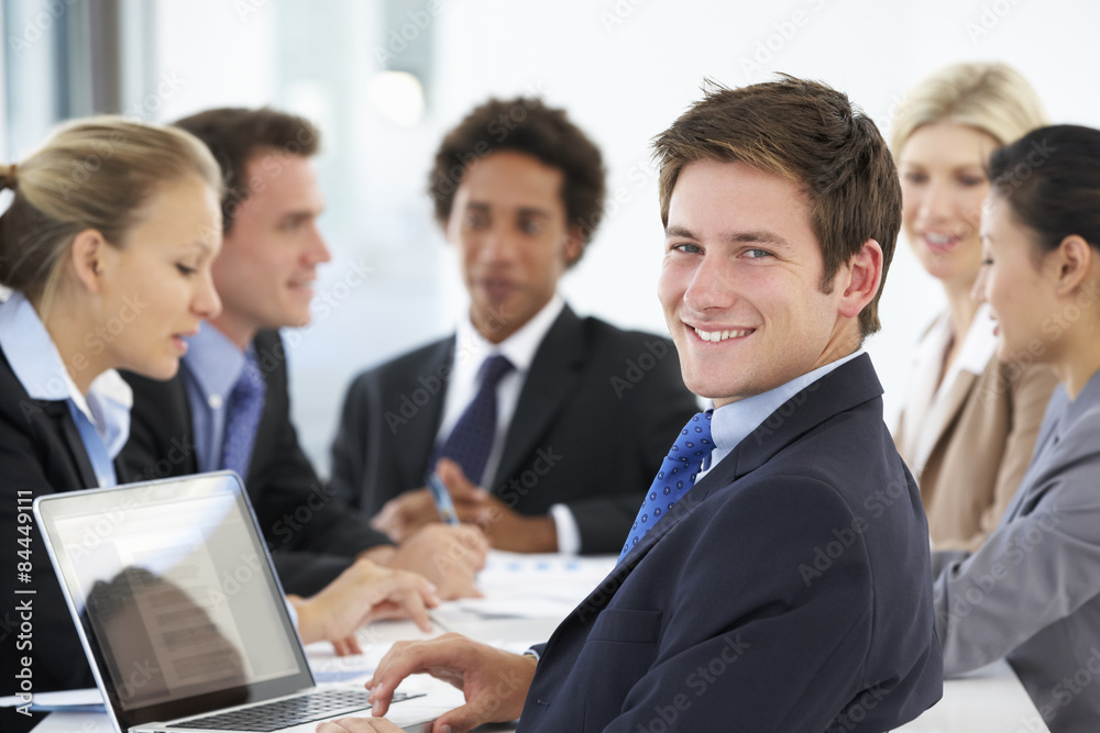 Portrait Of Male Executive With Office Meeting In Background Portrait Of Male Executive With Office Meeting In Background