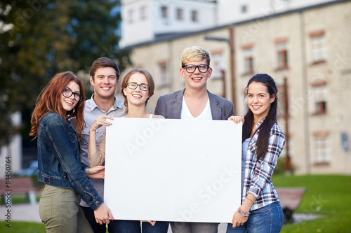 happy teenage students holding white blank board © Syda Productions