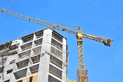 Crane and building construction site against blue sky