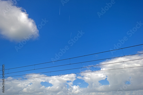 Lines of a catenary under a blue cloudy sky