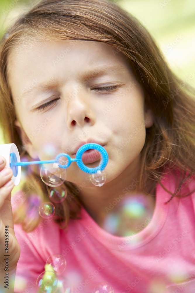 Head And Shoulders Portrait Of Girl Blowing Bubbles