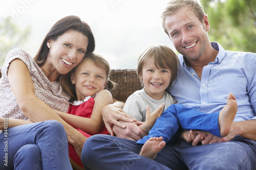 Family Sitting  On Garden Seat Together