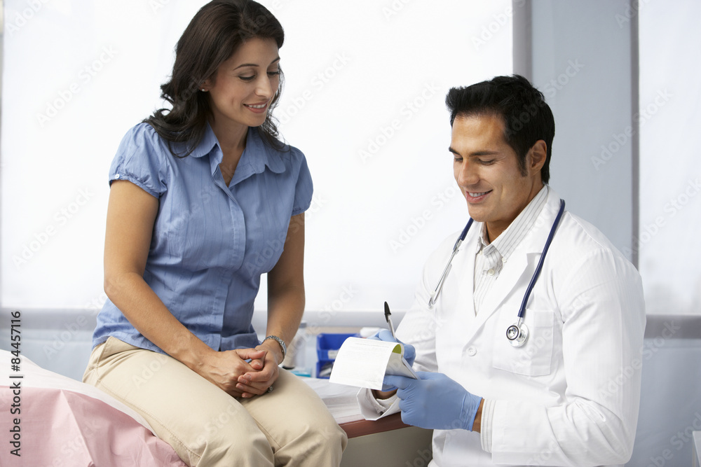 Doctor In Surgery With Female Patient Writing Prescription Doctor In Surgery With Female Patient Writing Prescription