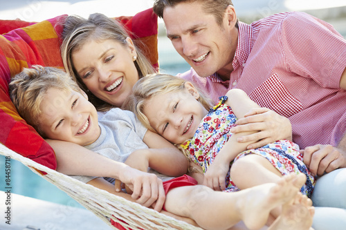 Family Relaxing In Garden Hammock Together