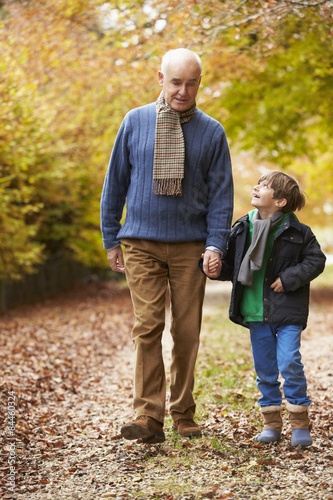 Grandfather And Grandson Walking Along Autumn Path