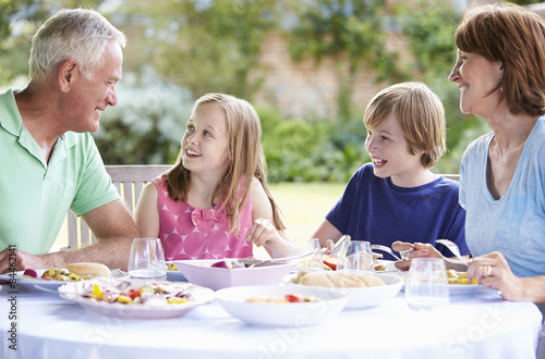 Grandparents With Grandchildren Enjoying Outdoor Meal © Monkey Business