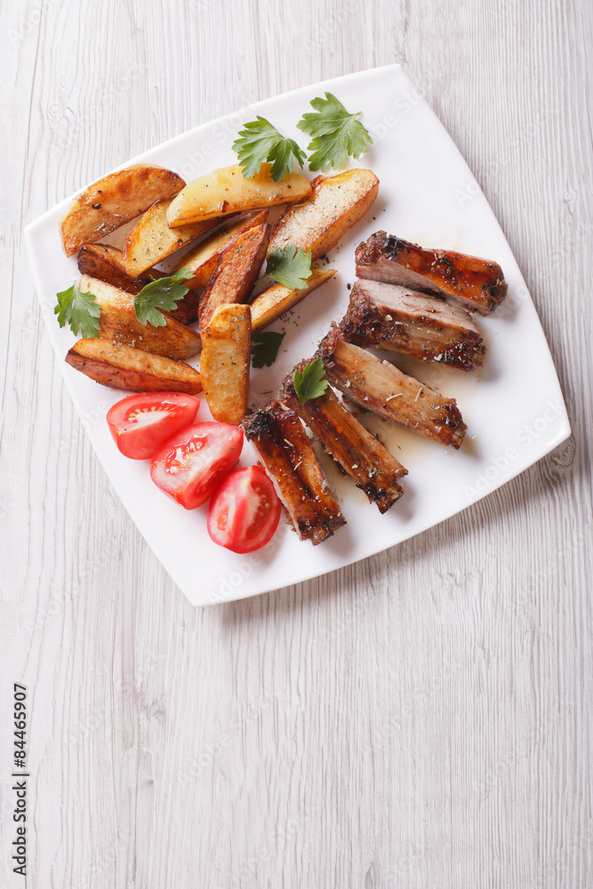 Pork ribs, potatoes and tomatoes on a plate top view vertical
Pork ribs, potatoes and tomatoes on a plate top view vertical